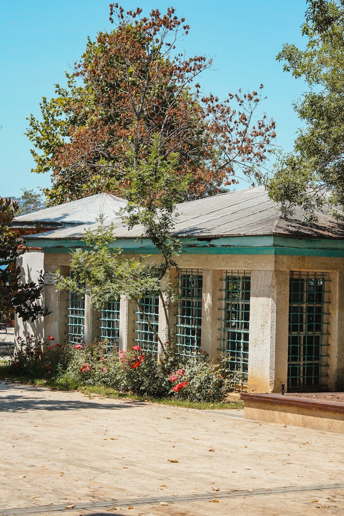 A charming historic building with gridded windows surrounded by trees and flowers in Istanbul, Turkey.