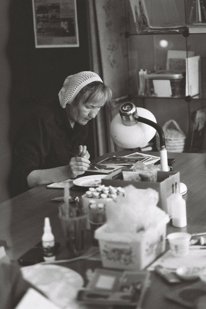 A woman absorbed in painting at her desk, captured in a classic black and white style.